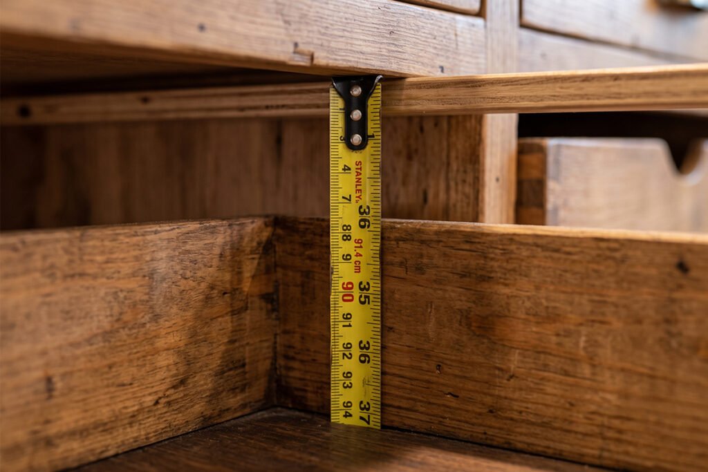 A tape measure checking vertical clearance inside a deep cabinet drawer
