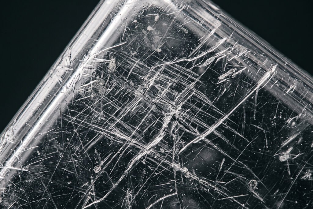 Close-up of a damaged, scratched plastic surface showing microscopic wear.