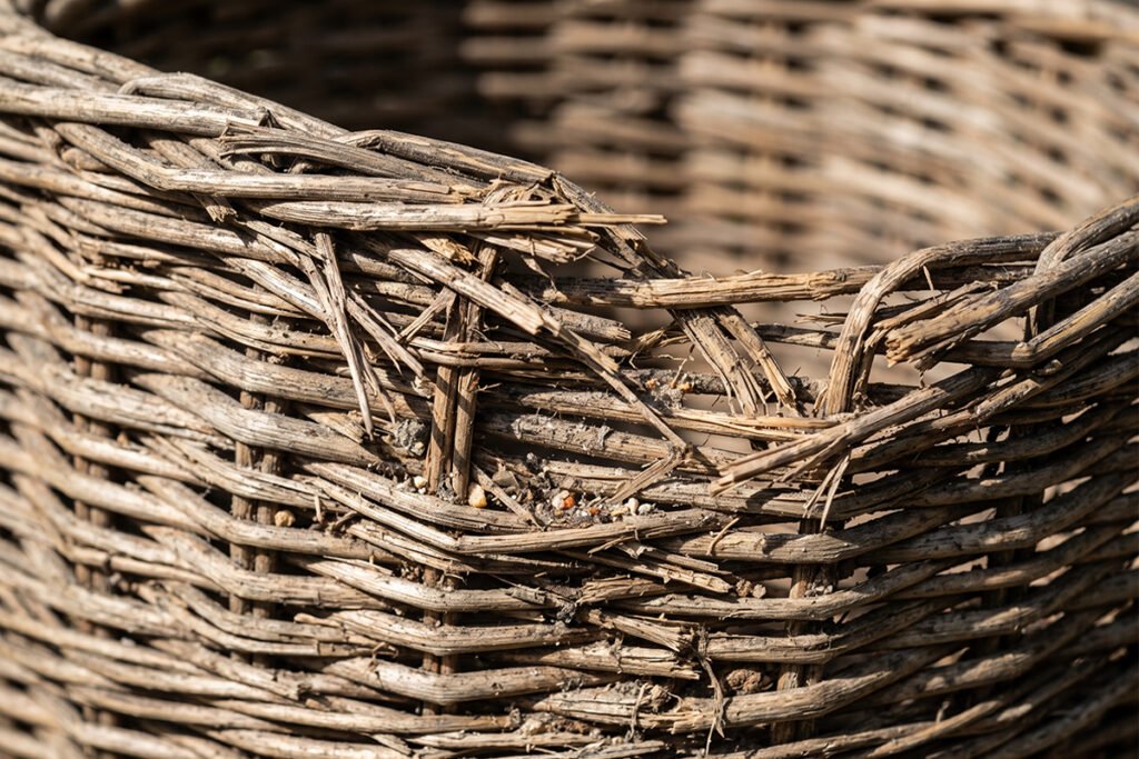 Close-up of frayed wicker basket weave showing trapped dust and debris
