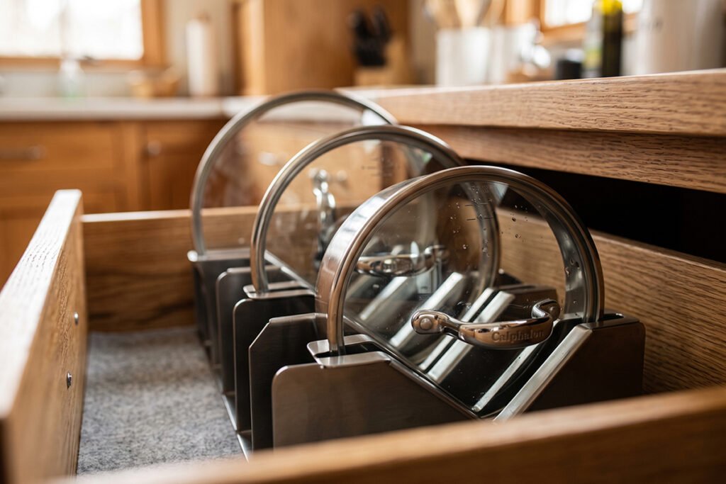 Close-up of pot lid handles fitting comfortably into angled organizer slots without touching drawer top