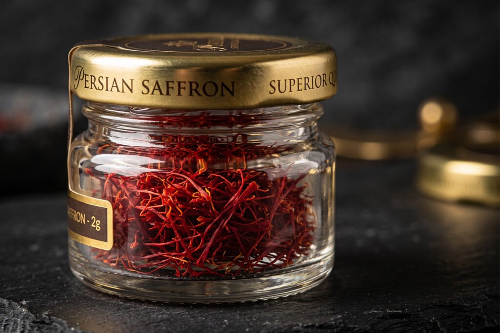 Crimson saffron threads stored in a small luxury glass jar with brass accents