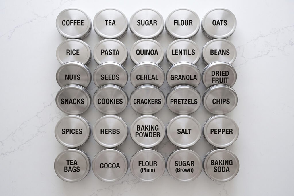 Neatly labeled stainless steel container lids viewed from an overhead angle