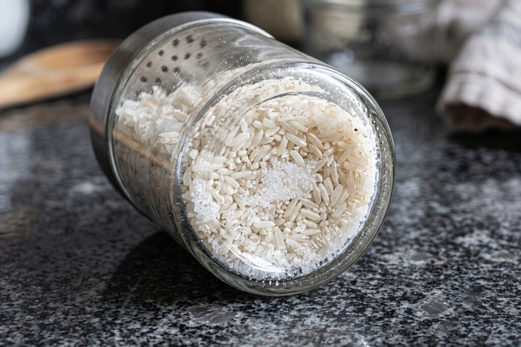 Uncooked white rice grains resting at the bottom of a clear glass spice shaker